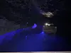 Mørk tunnel med blått lys og utstyr plassert langs høyre side.