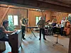 Musikere øver i en rustikk låve med instrumenter og mikrofoner.
