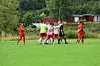 Fotballspillere i rødt og hvitt samles på en gressbane med dommer i svart.