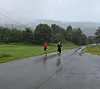 To løpere på en våt vei i et grønt, tåket landskap.
