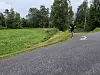 En løper på en svingete asfaltvei ved siden av grønt gras og trær.