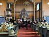 Musikere opptrer i en kirke mens publikum sitter på benker og stoler i skipet.