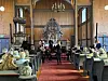 Musikere opptrer i en kirke mens publikum sitter på benker og stoler i skipet.