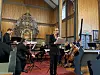 Musikere spiller klassisk musikk i en kirke med orgel, rødt teppe og store trevegger.
