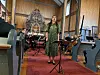 En sanger står foran et ensemble med piano og strykere i en kirke.