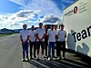 En gruppe personer står på en vei ved siden av en hvit buss med Teamster-logo.