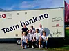Flere personer står og sitter foran en hvit varebil med teksten «Team bank.no».