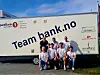 En gruppe står foran en hvit varebil med teksten Team bank.no og sponsorlogoer.