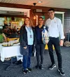 Fire personer poserer foran en restaurant med et serveringsbord i bakgrunnen.