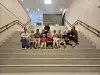 Gruppe mennesker sitter og står samlet i en innendørs trappegang.