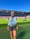 Frivillig med adgangskort står på fotballbanen foran en fullsatt stadion.