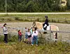 Barn står ved et gjerde og ser på en rytter på en fjordhest.