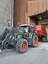Grønn traktor med stor rød henger.