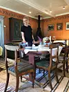 Person ved et dekket spisebord i en rustikk spisestue med vedovn og trepanel.