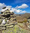Lavkledde steiner i forgrunnen foran et fjellandskap under blå himmel.