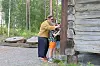 Voksen og barn ved inngangen til en tømmerhytte i en skog.
