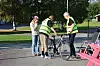 To personer undersøker en svart sykkel på en parkeringsplass.