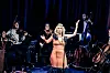 Vokalist synger midt på scenen mens musikere spiller i bakgrunnen.