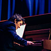Pianist spiller på et flygel i blått scenelys.