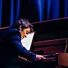 Pianist spiller på et flygel i blått scenelys.