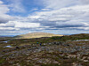 Åpent steinlandskap ved Raufjellet med lave fjellrygger og skyer over.