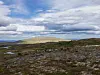 Åpent steinlandskap ved Raufjellet med lave fjellrygger og skyer over.