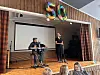 To unge musikere opptrer på en scene med keyboard, mikrofon og tallet 50 over seg.