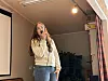 Kvinne synger i mikrofon i et lite innendørslokale.