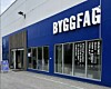 Blå Byggfag-butikk med store vinduer og inngang på gateplan.
