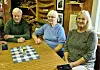 Tre personer rundt et bord i et treinnredet rom.