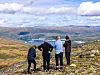 Fire turgåere ser utover et fjellandskap med innsjøer og daler.