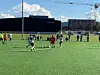 Fotballspillere kjemper om ballen på en kunstgressbane under blå himmel.