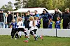 Unge fotballspillere konkurrerer om ballen foran tilskuere ved en gressbane.