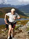 Terrengløper med nummer 010 løper på en steinete sti i fjellandskap.
