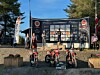 Flere motorsykler står foran en scene med sponsorplakater under et utendørs arrangement.