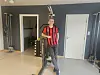 Person i rød- og svartstripet trøye står ved arbeidsutstyr i en garasje.