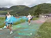 Løpere dekket av fargepulver deltar i et løp foran grønne fjell.