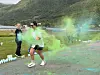 Løper i grønt beveger seg gjennom grønn og blå farget røyk i et fjellandskap.