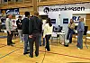 Mennesker besøker informasjonsboder på en messe i en idrettshall.