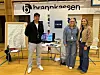 Tre personer ved en informasjonsstand med kart, skjermer og Thon-logoer.