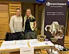To kvinner ved en Brannkassen-stand med brosjyrer og informasjonsmateriell.