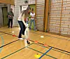Kvinne med kølle fører en ball mellom kjegler på et merket idrettsgulv.