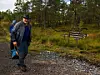 To turgåere på en grussti i skogen ved siden av et skilt.