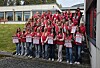 Ungdomsgruppe i røde klær står samlet med plakater utendørs.