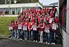 Ungdomsgruppe i røde klær står samlet med plakater utendørs.