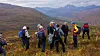 Gruppe turgåere med sekker i høstfjellet, omgitt av fargerik vegetasjon og fjell.