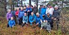 Stor gruppe turgåere i fargerike klær samlet i skogen.