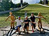 Personer og trefigurer poserer på en gangvei ved et skihoppanlegg.