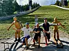 Personer og trefigurer poserer på en gangvei ved et skihoppanlegg.