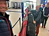 Reisende med skiutstyr og bagasje i en flyplassterminal.